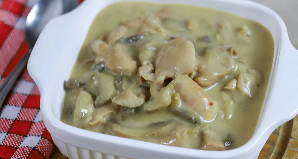 A step-by-step visual guide to making creamy rotisserie chicken mushroom soup. In the foreground, a wooden cutting board with diced onions, garlic, and sliced mushrooms. Warm lighting illuminates the ingredients, casting soft shadows. In the middle ground, a large pot simmering on a gas stove, steam rising from the savory broth. Shredded rotisserie chicken is being gently folded into the pot. In the background, a cozy kitchen setting with copper pots and pans hanging above the stove, creating a rustic, homely atmosphere. The scene is captured from a slightly elevated angle, emphasizing the layers of preparation and the comforting nature of this hearty, creamy soup.
